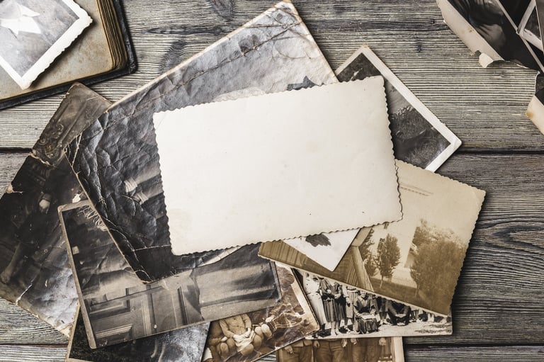 Scattered family photographs on a wooden table with a blank card